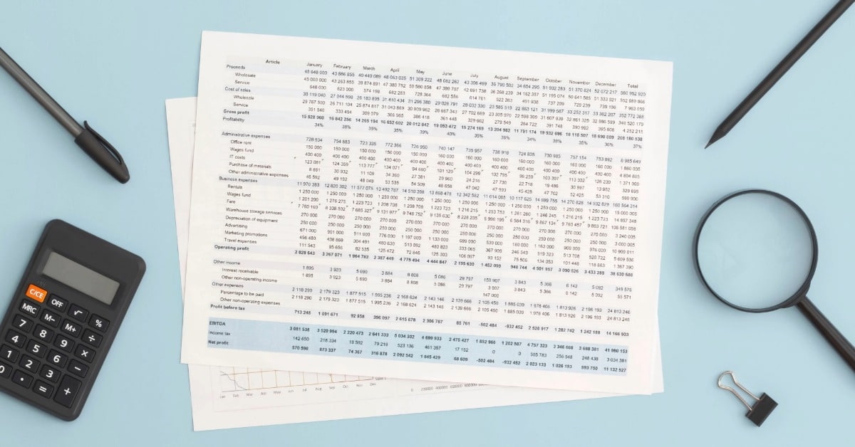 Planilha de controle de gastos impressa em uma mesa junto com calculadora e canetas